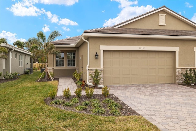 view of front facade featuring central AC, a garage, and a front yard