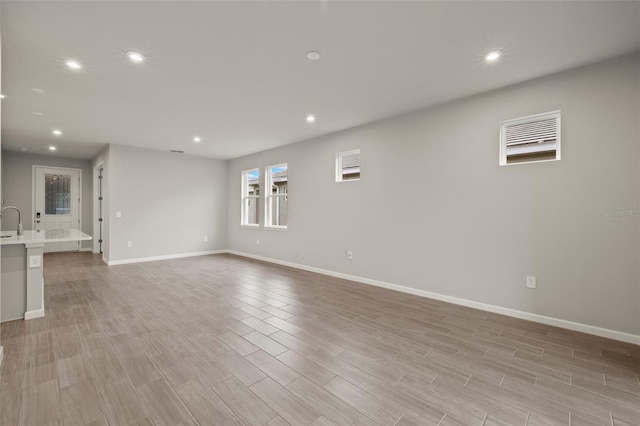 unfurnished living room with sink and light hardwood / wood-style flooring