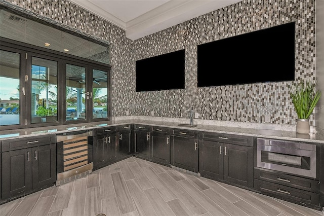 bar featuring wine cooler, ornamental molding, wall oven, light stone countertops, and backsplash