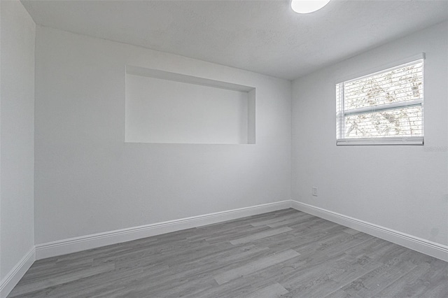 empty room with hardwood / wood-style floors and a textured ceiling