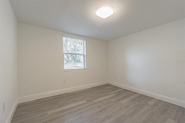 empty room with a textured ceiling and light wood-type flooring