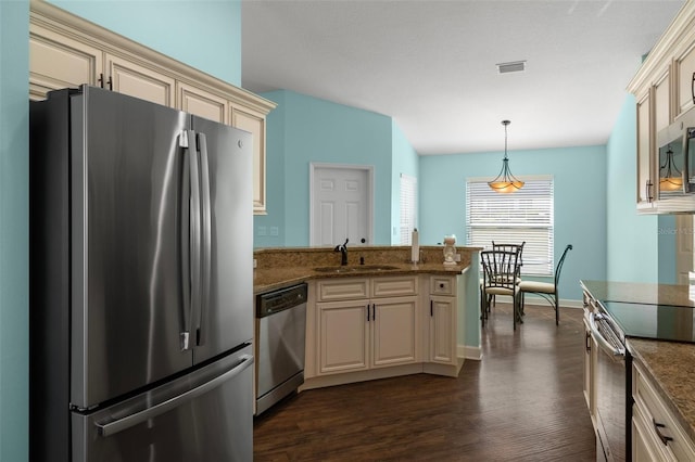 kitchen with sink, stainless steel appliances, dark hardwood / wood-style floors, cream cabinets, and decorative light fixtures