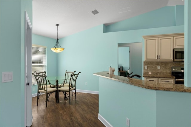 kitchen featuring appliances with stainless steel finishes, dark hardwood / wood-style flooring, backsplash, pendant lighting, and cream cabinetry