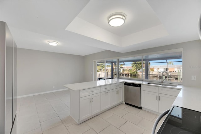 kitchen featuring kitchen peninsula, dishwasher, range, a raised ceiling, and white cabinets