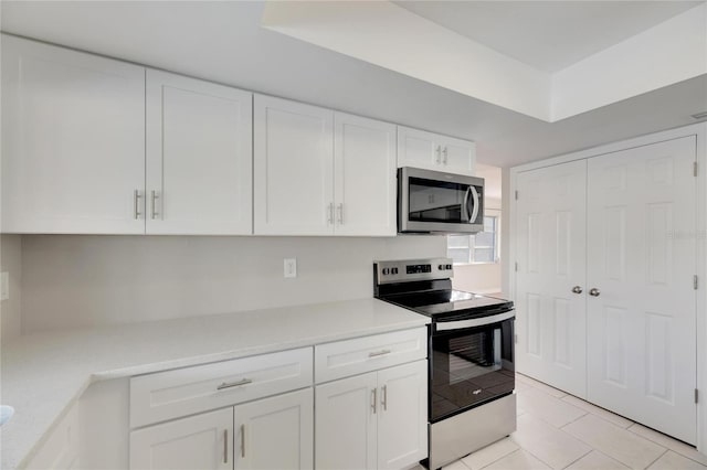 kitchen featuring appliances with stainless steel finishes, white cabinets, and light tile patterned floors