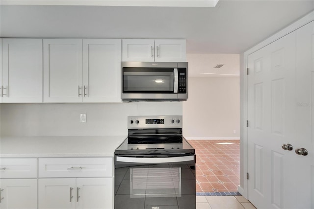 kitchen with stainless steel appliances, light tile patterned flooring, and white cabinetry