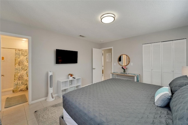 tiled bedroom featuring a textured ceiling, ensuite bathroom, and a closet