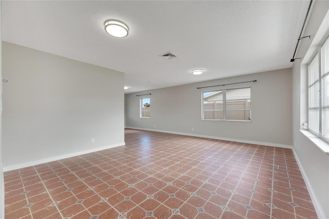 empty room with a textured ceiling and tile patterned floors