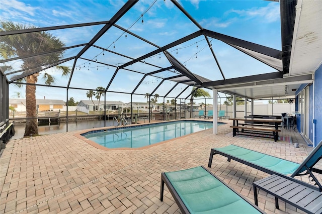 view of pool featuring a patio, a water view, and glass enclosure