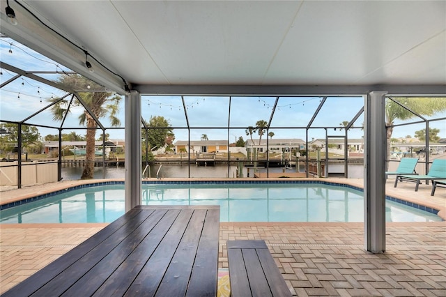 view of swimming pool with a patio area, glass enclosure, and a water view