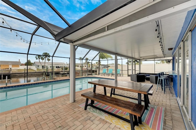 view of pool with a lanai, a water view, and a patio area