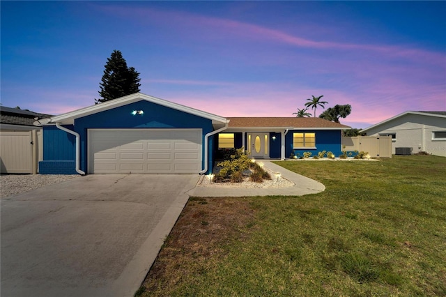 ranch-style house with central air condition unit, a yard, and a garage