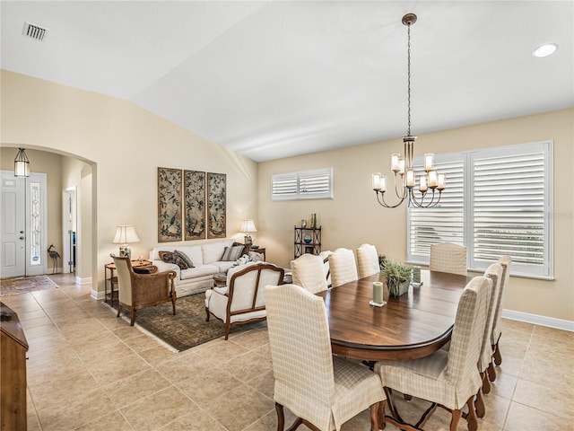 dining area with lofted ceiling, a notable chandelier, and light tile patterned flooring