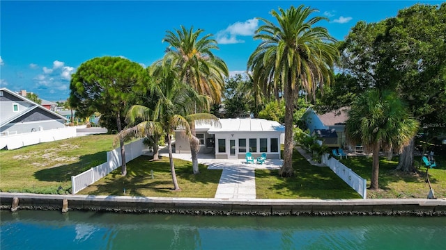 back of house with a water view, a patio area, and a lawn