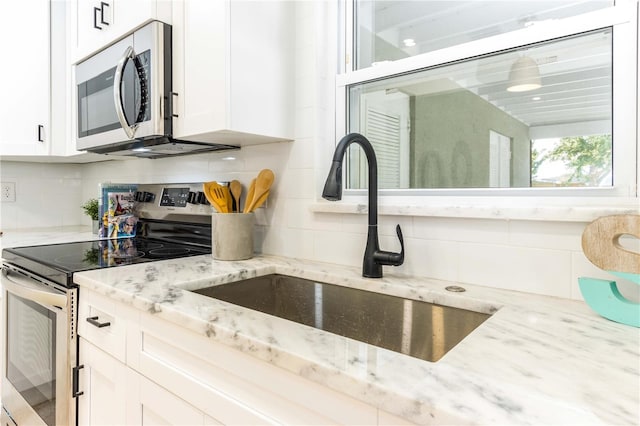 kitchen featuring decorative backsplash, appliances with stainless steel finishes, and white cabinetry