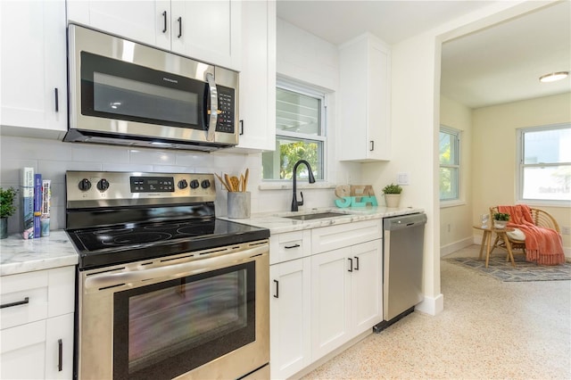 kitchen with tasteful backsplash, light stone countertops, sink, and stainless steel appliances