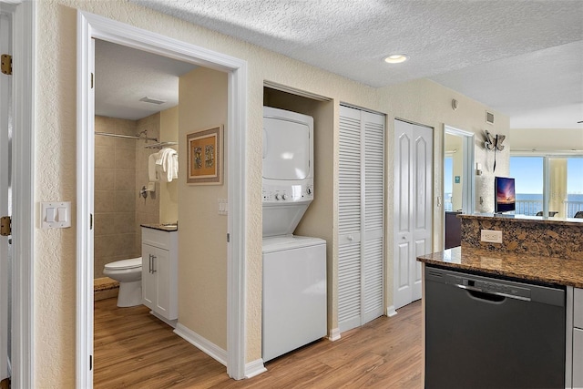 kitchen with white cabinetry, dishwasher, light hardwood / wood-style floors, and stacked washer / drying machine