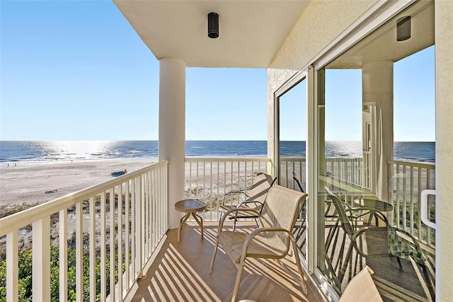 balcony featuring a water view and a beach view