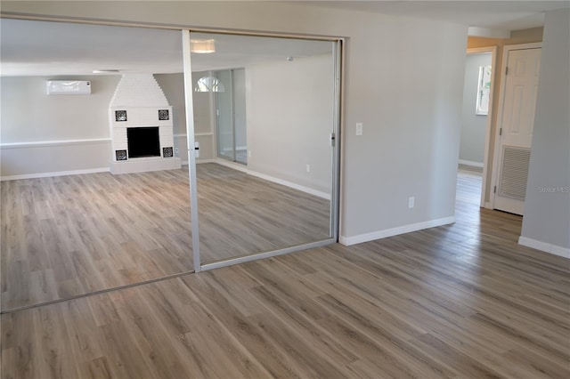 unfurnished bedroom featuring a closet, wood-type flooring, and a brick fireplace