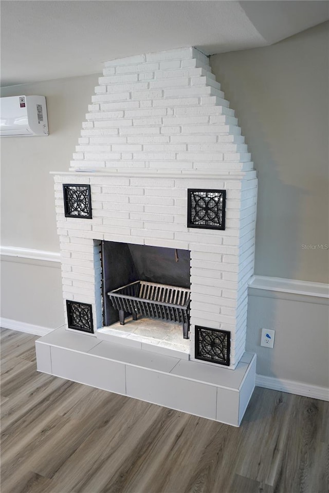 room details featuring a wall mounted AC, a tiled fireplace, and hardwood / wood-style flooring