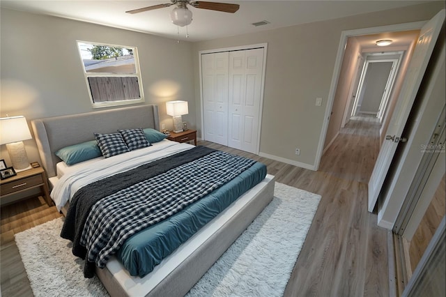 bedroom featuring a closet, baseboards, a ceiling fan, visible vents, and light wood finished floors