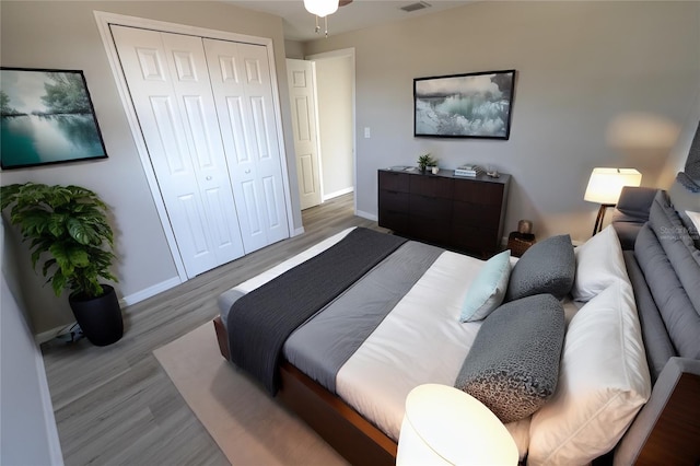 bedroom featuring visible vents, a closet, baseboards, and wood finished floors
