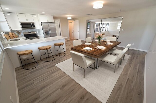 dining area featuring baseboards, light wood-type flooring, and recessed lighting