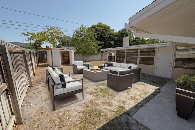 view of patio / terrace with an outbuilding, an outdoor living space with a fire pit, and a fenced backyard