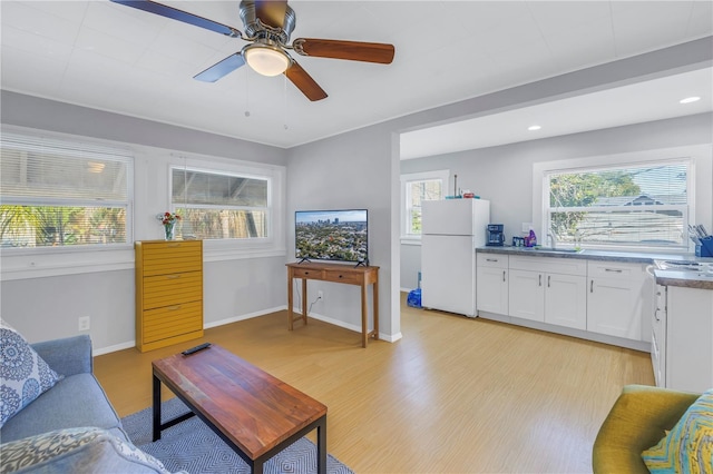 living room featuring light hardwood / wood-style flooring, ceiling fan, and sink