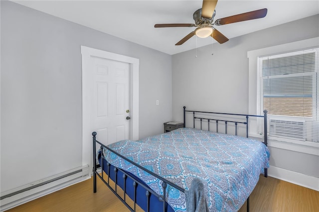 bedroom featuring wood-type flooring, a baseboard radiator, and ceiling fan