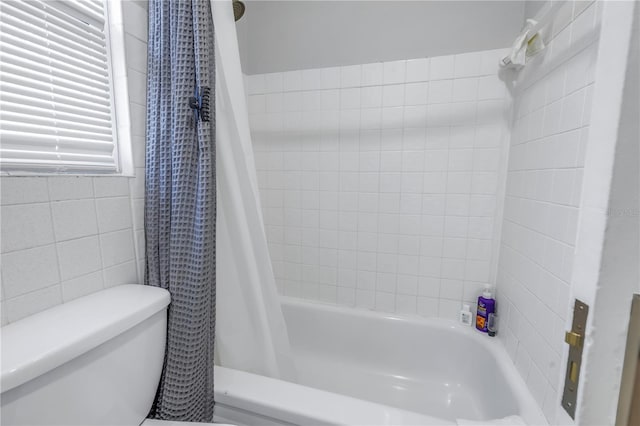 bathroom featuring toilet, shower / bath combo with shower curtain, and tile walls