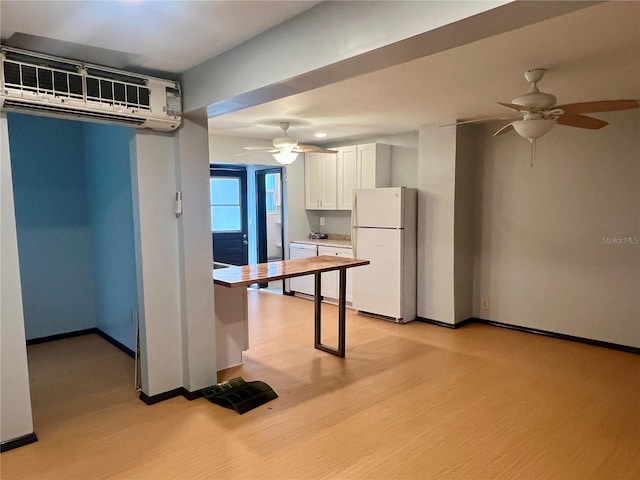 kitchen with a wall mounted air conditioner, white cabinetry, white appliances, and light hardwood / wood-style floors