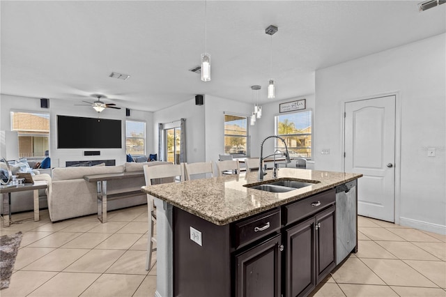 kitchen featuring stainless steel dishwasher, hanging light fixtures, a wealth of natural light, and an island with sink