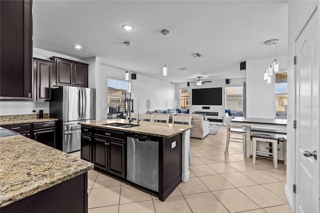 kitchen featuring appliances with stainless steel finishes, plenty of natural light, a kitchen island with sink, sink, and hanging light fixtures