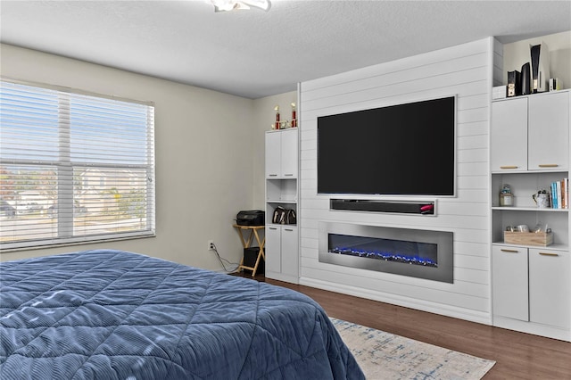 bedroom featuring a fireplace, a textured ceiling, and dark wood-type flooring