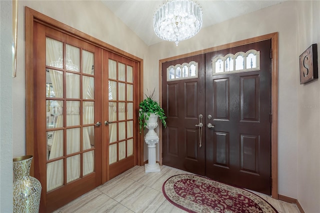 tiled foyer entrance with french doors, lofted ceiling, and a notable chandelier