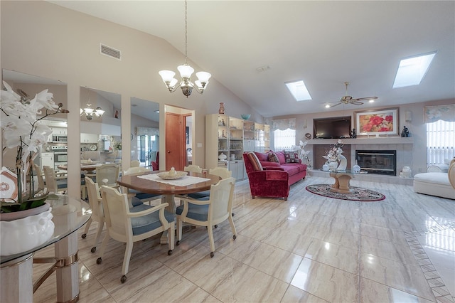 dining space featuring a fireplace, high vaulted ceiling, and ceiling fan with notable chandelier