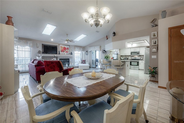 tiled dining room with ceiling fan with notable chandelier and lofted ceiling with skylight