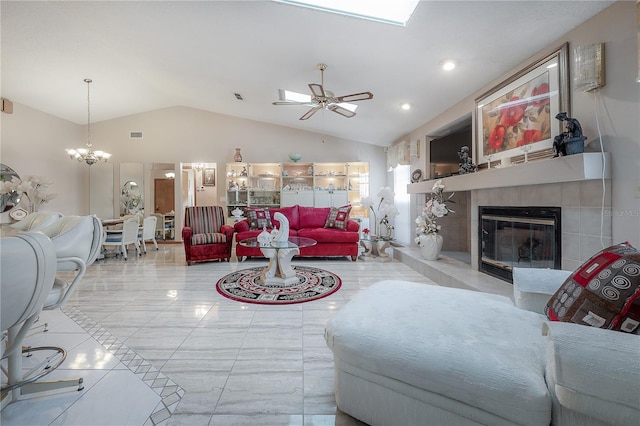 living room featuring a tiled fireplace, light tile patterned floors, ceiling fan with notable chandelier, and vaulted ceiling