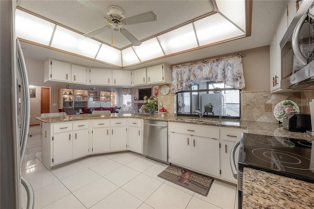 kitchen with kitchen peninsula, sink, white cabinets, and stainless steel appliances