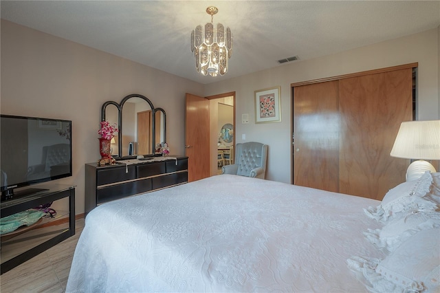 bedroom with a closet, light wood-type flooring, and a chandelier