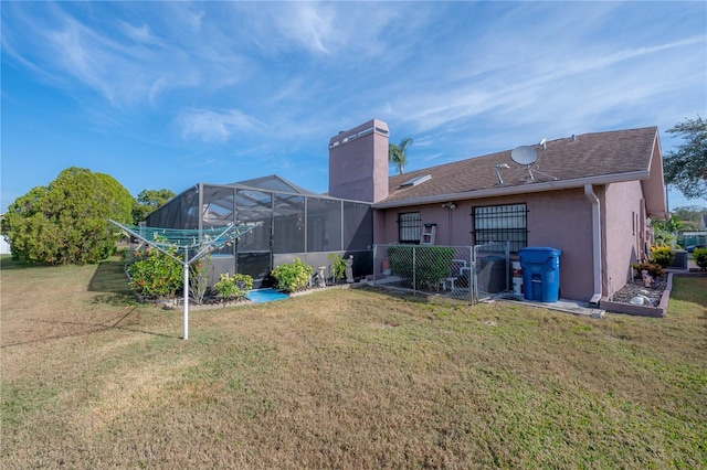 rear view of house featuring a lanai and a lawn