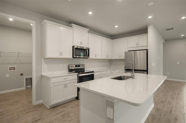 kitchen featuring appliances with stainless steel finishes, sink, a center island with sink, and white cabinets