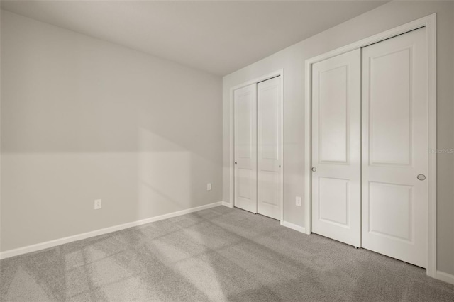 unfurnished bedroom with carpet floors and multiple closets