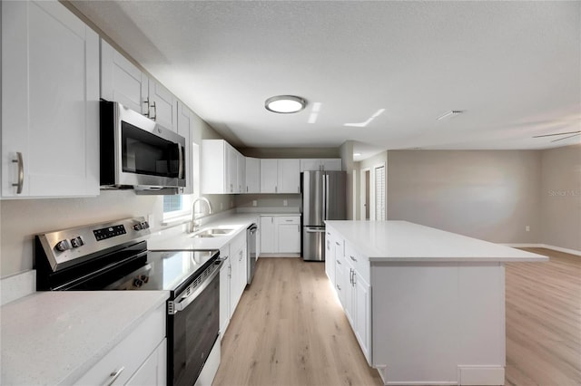 kitchen with white cabinets, a kitchen island, sink, and stainless steel appliances