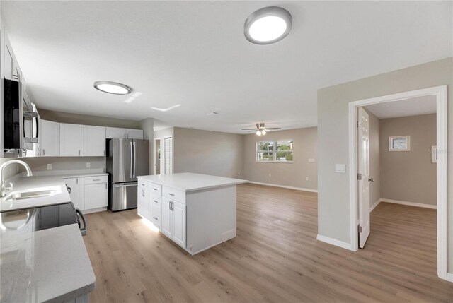 kitchen with stainless steel appliances, sink, light hardwood / wood-style flooring, white cabinets, and a center island