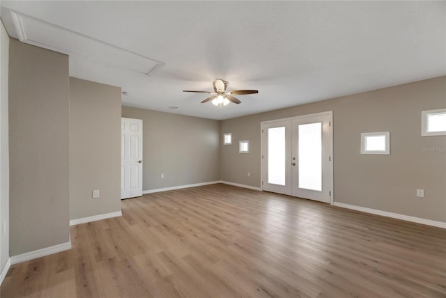 empty room with french doors, light wood-type flooring, and ceiling fan