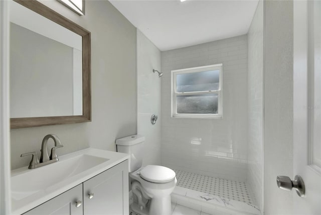 bathroom with tiled shower, vanity, and toilet