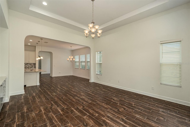 empty room featuring a healthy amount of sunlight, dark hardwood / wood-style floors, and a notable chandelier