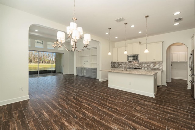 kitchen with appliances with stainless steel finishes, dark wood-type flooring, pendant lighting, a notable chandelier, and white cabinetry